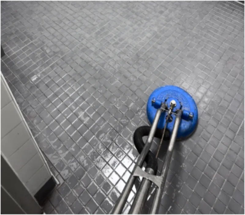 Rotary tile and grout cleaning tool on a gray mosaic floor